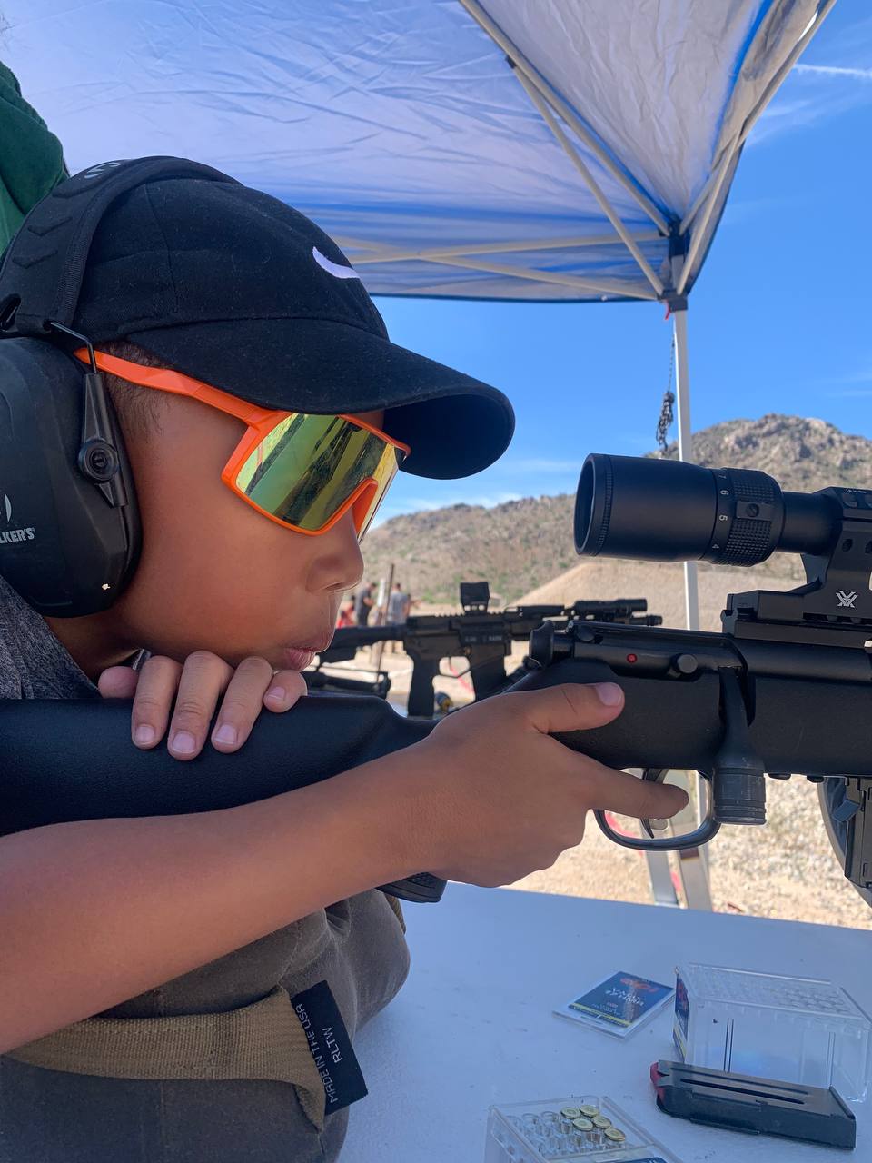Sovereign King, age 5, behind a suppressed 17 HMR — proper ear pro, steady cheek weld, desert range day
