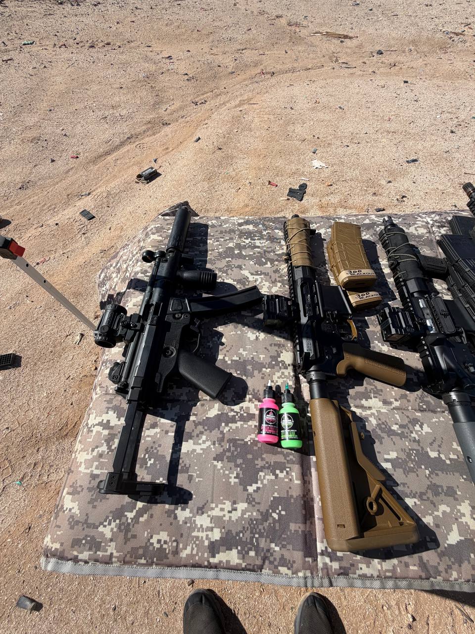 Desert range spread — SBR, 300 BLK carbine, and precision rifle on the mat