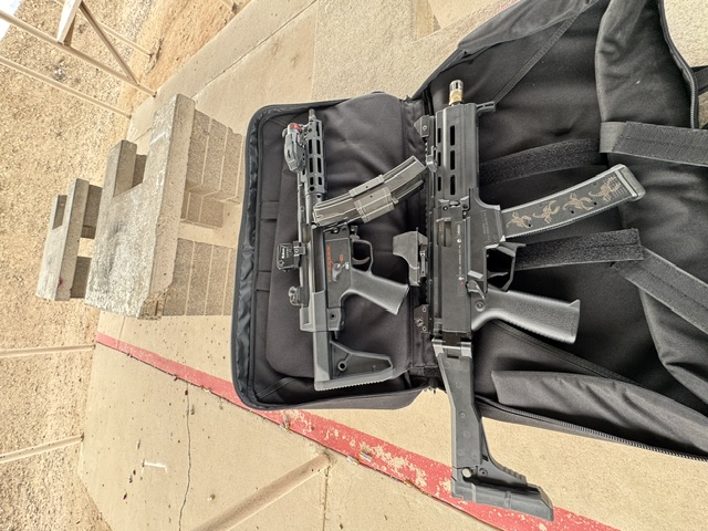 Twin PDWs — red dot equipped and bagged for the desert range